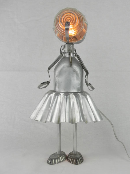 Gourdol. Personnage féminin avec gourde et moule à gâteau en aluminium. Assemblage lumineux d'un bol, deux mini moules et une pince à escargot. Lampe figurative